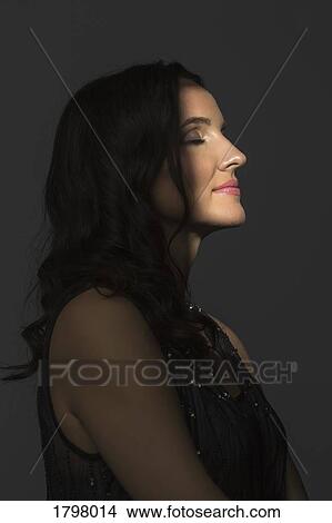 Picture - Portrait of beautiful woman with eyes closed in side profile and amidst shadow. Fotosearch