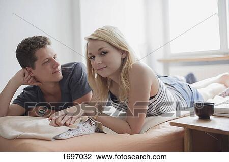 Portrait of beautiful young woman lying by boyfriend on bed at home View Large Photo Image Stock Image - Portrait of beautiful young woman lying by boyfriend on bed at home. Fotosearch
