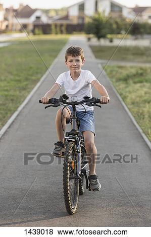 Portrait of boy cycling on footpath View Large Photo Image Stock Photo - Portrait of boy cycling on footpath. Fotosearch
