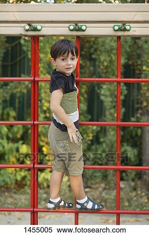 Stock Photography - Portrait of boy standing on climbing wall at park. Fotosearch
