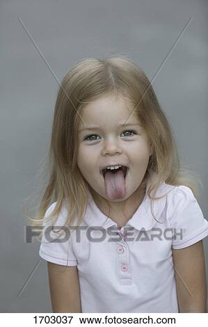 Portrait of cheerful girl sticking out tongue against gray background View Large Photo Image Stock Photo - Portrait of cheerful girl sticking out tongue against gray background. Fotosearch