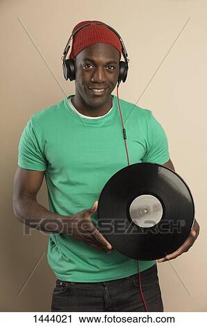 Stock Image - Portrait of confident DJ holding record . Fotosearch