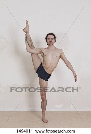Stock Image - Portrait of confident man doing yoga against white background. Fotosearch