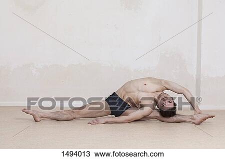 Stock Image - Portrait of confident man performing revolved head-to-knee yoga pose. Fotosearch