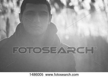 Stock Photography - Portrait of confident man standing outdoors during sunny day. Fotosearch