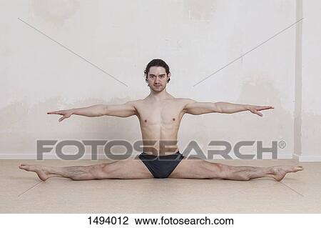 Portrait of confident man with arms outstretched doing splits while performing yoga View Large Photo Image Stock Image - Portrait of confident man with arms outstretched doing splits while performing yoga. Fotosearch