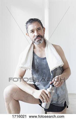 Portrait of confident mature man holding water bottle against wall View Large Photo Image Stock Image - Portrait of confident mature man holding water bottle against wall. Fotosearch
