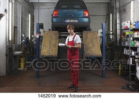 Stock Photo - Portrait of confident mechanic holding clipboard at garage. Fotosearch