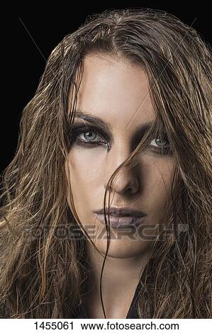 Stock Image - Portrait of confident woman against black background. Fotosearch