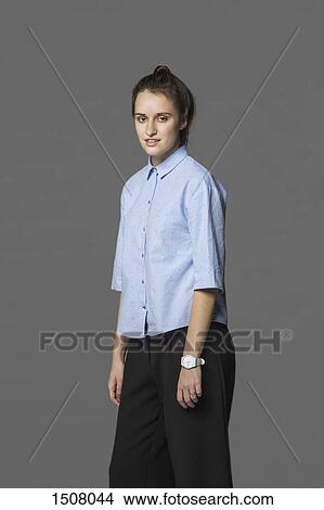 Picture - Portrait of confident woman standing against gray background. Fotosearch