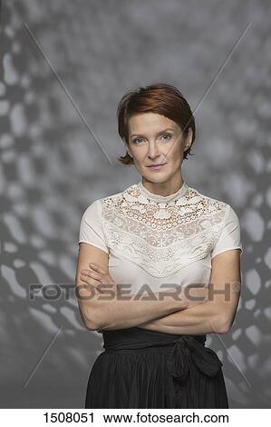 Stock Image - Portrait of confident woman standing against gray background. Fotosearch