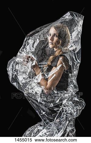 Portrait of confident woman wrapped in plastic against black background View Large Photo Image Stock Photography - Portrait of confident woman wrapped in plastic against black background. Fotosearch