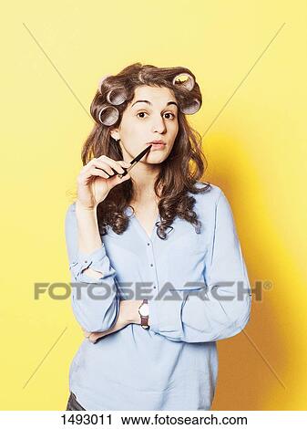 Portrait of confident young woman wearing hair curlers against yellow background View Large Photo Image Stock Image - Portrait of confident young woman wearing hair curlers against yellow background. Fotosearch