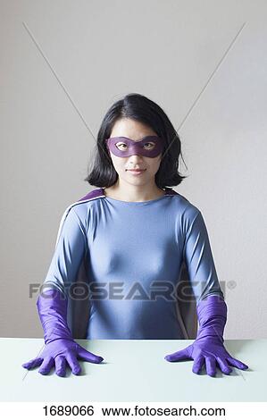 Portrait of confident young woman dressed as superhero against white wall View Large Photo Image Stock Photograph - Portrait of confident young woman dressed as superhero against white wall. Fotosearch