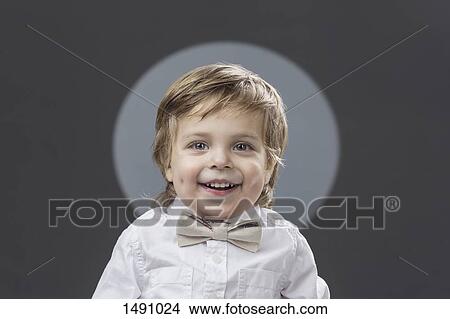 Picture - Portrait of cute boy with bowtie against gray background. Fotosearch