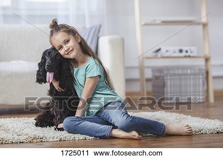 Portrait of cute girl embracing dog while sitting on rug at home View Large Photo Image Stock Image - Portrait of cute girl embracing dog while sitting on rug at home. Fotosearch