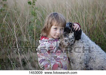 Stock Photo - Portrait of cute girl sitting with dog on field. Fotosearch