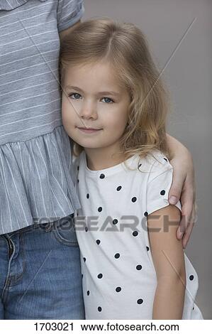 Portrait of cute girl standing by mother against gray background View Large Photo Image Stock Image - Portrait of cute girl standing by mother against gray background. Fotosearch