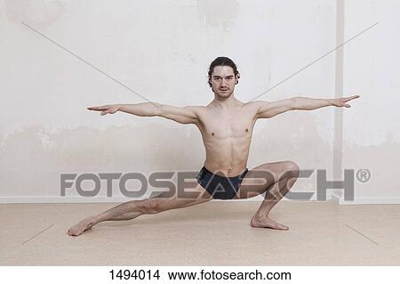 Picture - Portrait of determined man practicing yoga in warrior position against white background. Fotosearch