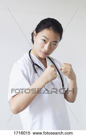 Portrait of female doctor in fighting stance against white wall View Large Photo Image Stock Photography - Portrait of female doctor in fighting stance against white wall. Fotosearch