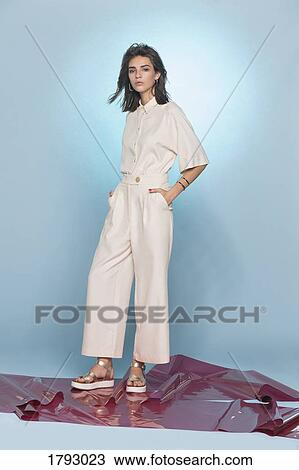 Stock Image - Portrait of female fashion model posing against blue background. Fotosearch