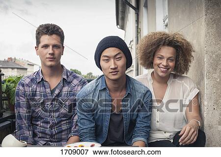 Portrait of friends sitting at balcony against sky View Large Photo Image Stock Photo - Portrait of friends sitting at balcony against sky. Fotosearch