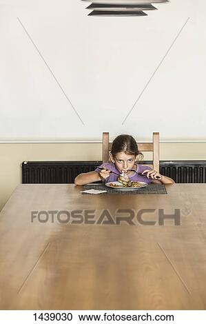 Portrait of girl eating food at dining table in house View Large Photo Image Stock Image - Portrait of girl eating food at dining table in house. Fotosearch