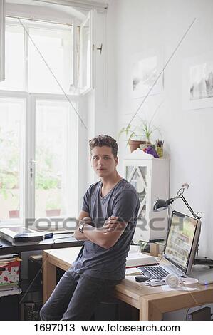 Portrait of handsome man leaning with arms crossed on table at home View Large Photo Image Stock Image - Portrait of handsome man leaning with arms crossed on table at home. Fotosearch