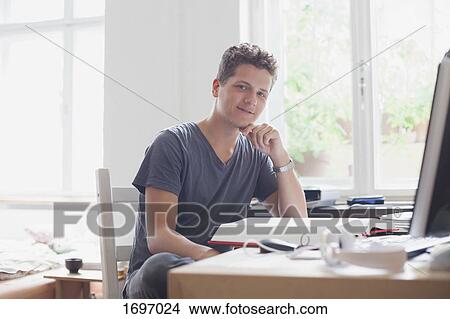 Picture - Portrait of handsome young male university student studying at home. Fotosearch