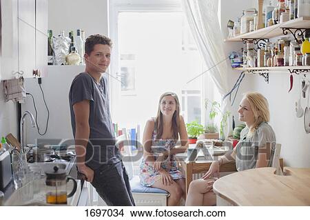 Portrait of handsome young man standing with female friends in kitchen at home View Large Photo Image Picture - Portrait of handsome young man standing with female friends in kitchen at home. Fotosearch