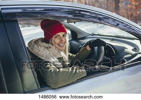 Stock Photograph - Portrait of happy beautiful woman driving car during winter. Fotosearch