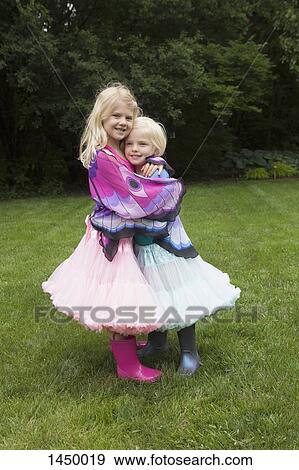 Portrait of happy girl hugging sister while standing in backyard View Large Photo Image Stock Photo - Portrait of happy girl hugging sister while standing in backyard. Fotosearch