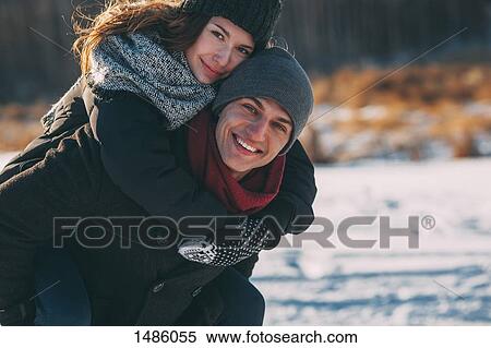 Portrait of happy man giving piggyback ride to woman during winter View Large Photo Image Stock Photography - Portrait of happy man giving piggyback ride to woman during winter. Fotosearch