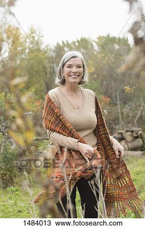 Portrait of happy mature woman at park during autumn View Large Photo Image Stock Image - Portrait of happy mature woman at park during autumn. Fotosearch