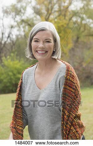 Portrait of happy mature woman standing at park during autumn View Large Photo Image Stock Photo - Portrait of happy mature woman standing at park during autumn. Fotosearch