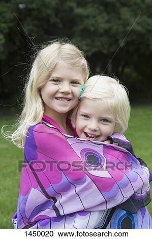 Portrait of happy sisters hugging while standing in backyard View Large Photo Image Stock Image - Portrait of happy sisters hugging while standing in backyard. Fotosearch