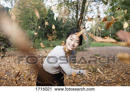 Portrait of happy woman throwing dry leaves in mid-air while standing at park during autumn View Large Photo Image Stock Image - Portrait of happy woman throwing dry leaves in mid-air while standing at park during autumn. Fotosearch