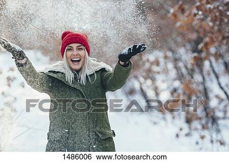 Portrait of happy young woman playing in snow View Large Photo Image Stock Photograph - Portrait of happy young woman playing in snow. Fotosearch