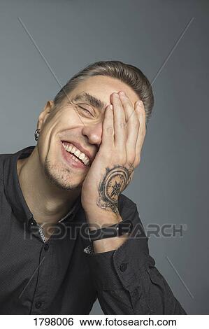 Portrait of man smiling with head in hands against gray background View Large Photo Image Stock Photograph - Portrait of man smiling with head in hands against gray background. Fotosearch