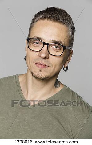 Stock Photograph - Portrait of man with glasses against gray background. Fotosearch