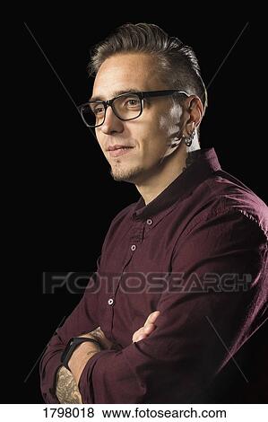 Portrait of man with glasses and arms crossed against black background View Large Photo Image Stock Photo - Portrait of man with glasses and arms crossed against black background. Fotosearch