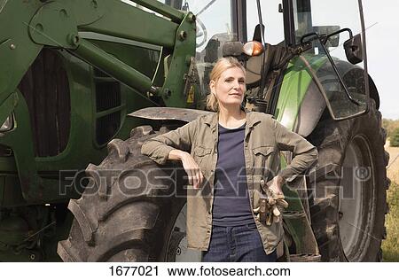 Portrait of mature woman standing by tractor on sunny day View Large Photo Image Stock Image - Portrait of mature woman standing by tractor on sunny day. Fotosearch