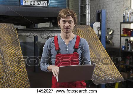 Portrait of mechanic holding laptop at garage View Large Photo Image Stock Photo - Portrait of mechanic holding laptop at garage. Fotosearch