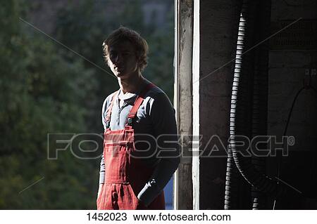 Stock Image - Portrait of mechanic standing in garage. Fotosearch