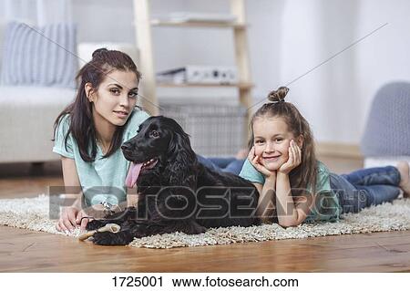 Portrait of mother and daughter lying with dog on rug at home View Large Photo Image Stock Image - Portrait of mother and daughter lying with dog on rug at home. Fotosearch