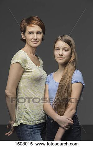 Stock Photography - Portrait of mother and daughter standing against gray background. Fotosearch