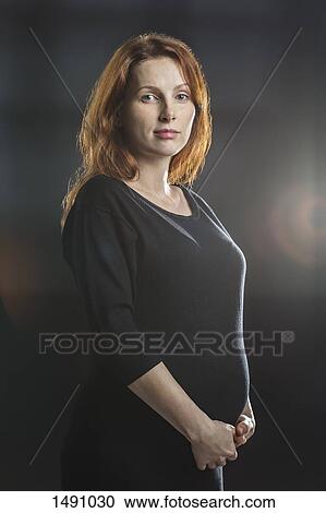 Portrait of pregnant woman touching stomach against gray background View Large Photo Image Stock Image - Portrait of pregnant woman touching stomach against gray background. Fotosearch