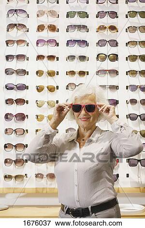 Portrait of senior woman wearing sunglasses while standing at store View Large Photo Image Stock Photo - Portrait of senior woman wearing sunglasses while standing at store. Fotosearch