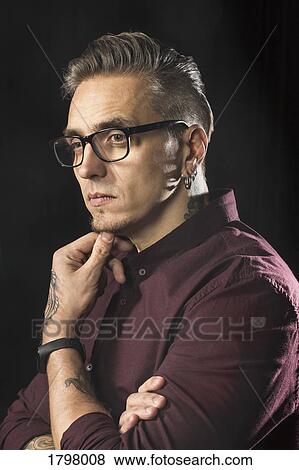 Portrait of serious man wearing glasses and looking away against black background View Large Photo Image Stock Photo - Portrait of serious man wearing glasses and looking away against black background. Fotosearch