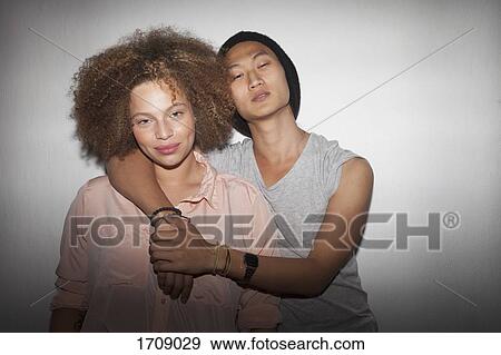 Portrait of smiling couple standing against wall View Large Photo Image Stock Photo - Portrait of smiling couple standing against wall. Fotosearch